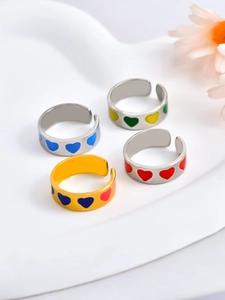 Detail of four stackable heart-shaped rings with colorful enamel on a white display tray