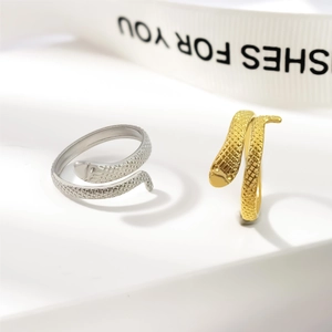 Adjustable gold and silver snake rings with textured scales on a clean minimalist pedestal