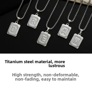 Detail of square titanium steel alphabet pendants with engraved letters on bold chain