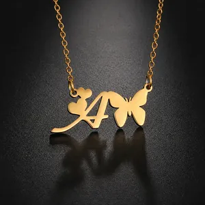 Détail du collier en acier titane doré avec pendentifs lettre A, cœur et papillon