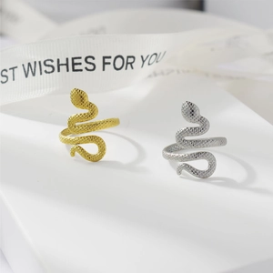 Close-up of gold and silver snake rings with scale texture on a gift box background