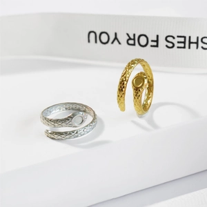 Macro shot of silver and gold snake wrap rings with detailed scale textures on white steps