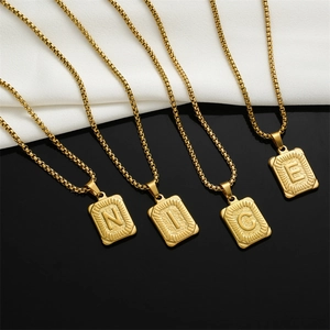 Detailed close-up of gold stainless steel rectangle letter pendants spelling NICE