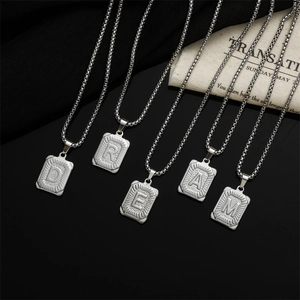 Detailed macro view of silver titanium steel square pendants spelling DREAM with sunburst texture