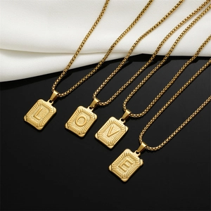 Detail of square gold initial pendants with engraved L-O-V-E letters on box chain