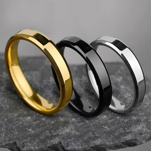 Polished silver, gold and black stainless steel rings with bevelled edges on a rock