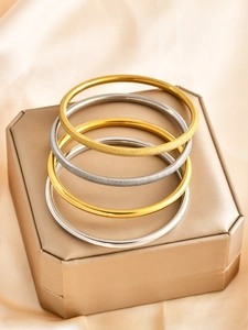 Macro detail of 6mm gold and silver bangles with polished and matte sand surfaces