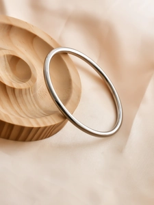 Polished silver 6mm minimalist bangle displayed on elegant silk and wooden tray