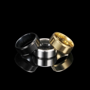 Detailed view of polished stainless steel rings in black, silver and gold with reflections