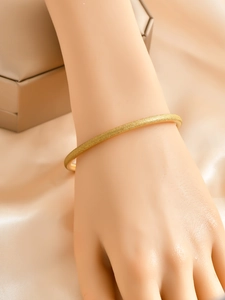 Close-up of minimalist gold matte bangle with starry sand finish worn on a model's wrist