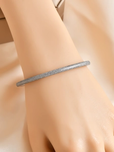 Detailed macro view of 6mm frosted matte texture on minimalist silver bangle on wrist
