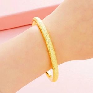 Close-up of a 6mm gold sandblasted solid bangle with textured matte finish on wrist