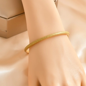 6mm matte gold bangle bracelet with sandblasted finish on champagne silk background