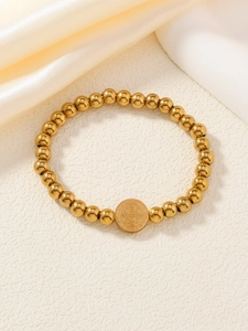 Détail d'un bracelet de perles dorées avec pendentif de pièce religieuse