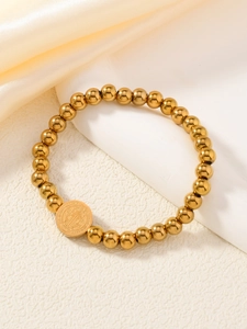 Détail du pendentif médaille Saint-Benoît doré sur bracelet de perles
