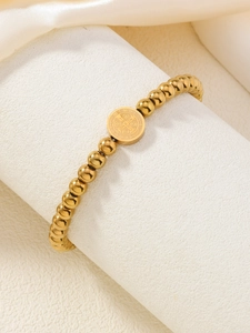 Gros plan du bracelet à perles dorées avec médaille religieuse Saint-Benoît sur soie