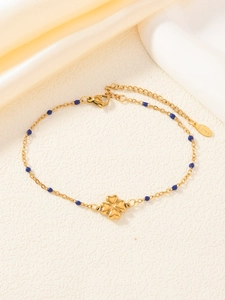 Dettaglio del ciondolo a quadrifoglio e perline blu su bracciale in acciaio dorato