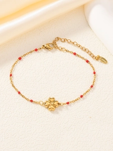 Dettaglio del bracciale in acciaio inossidabile dorato con perline rosse e quadrifoglio