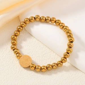 Bracelet à perles dorées avec médaille religieuse San Benito sur fond de satin
