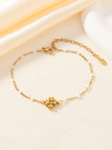 Dettaglio del bracciale con ciondolo a quadrifoglio e perline su catena in acciaio oro
