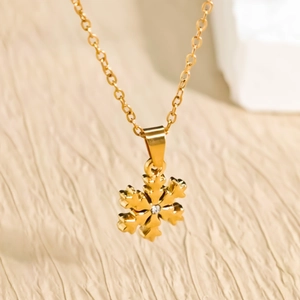 Elegant gold snowflake pendant necklace with white zircon on warm textured background