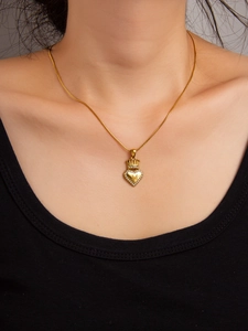 Detail showing gold heart crown pendant with letter M and zircon on model neck