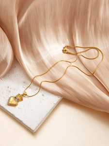 Macro shot of gold heart pendant with crown and letter Z on luxury silk background