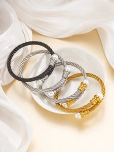 Dettaglio di tre bracciali rigidi a fune intrecciata in oro, argento e nero titanio