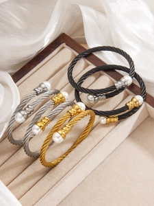 Dettaglio di bracciali a cavo intrecciato con perle in oro argento e finitura nera