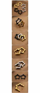 Macro shot of minimalist star-shaped steel earrings in black, gold, and silver finishes