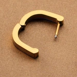 Polished gold U-shaped titanium steel hoop earring on brown textured fabric background