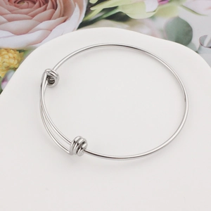 Polished silver adjustable stainless steel spring coil bangle on a ceramic tray