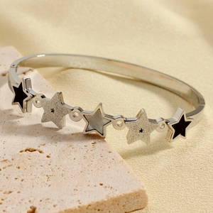 Star-shaped stainless steel bangle with enamel and mother of pearl inlay on travertine
