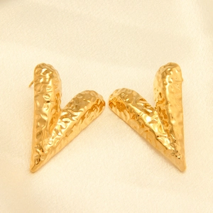 Detalle de pendientes en V de acero chapado en oro de 18k con textura lava martillada