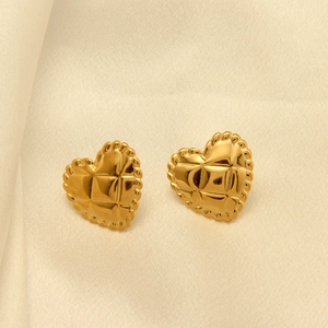 Detalle de pendientes de corazón dorados con textura acolchada y bordes festoneados