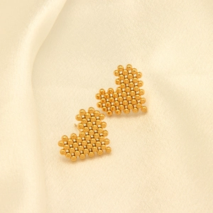 Detalle macro de pendientes de corazón en acero chapado en oro de 18k con malla de cuentas