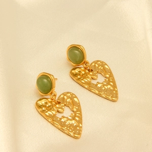 Vista macro de pendientes vintage con piedras verdes y corazones dorados martillados