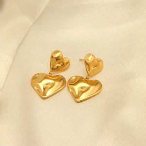 Pendientes de doble corazón chapados en oro de 18 quilates sobre elegante fondo de seda beis