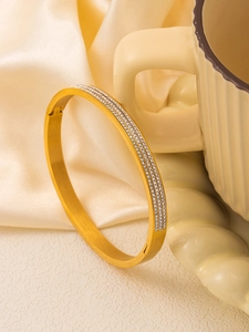 Detailed close-up of golden titanium steel bracelet with triple rows of zircon stones