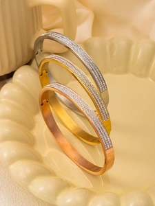 Detail view of gold, silver, and rose gold bracelets featuring three rows of crystals