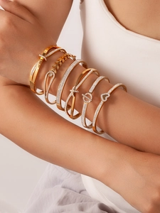 Detail of stacked gold bangle set with screw patterns and pavé crystals on a model arm