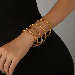 Set van vier goudkleurige stalen armbanden met gedraaide, kralen en bamboe textuur designs