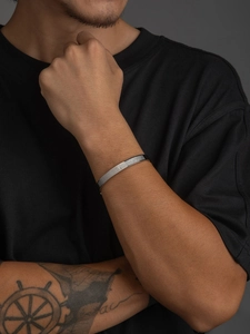 Primer plano detallado del brazalete de acero plateado con grabado de cruz y escrituras