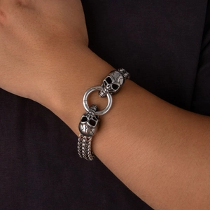 Detalle de una pulsera punk de calavera doble en acero inoxidable con cadena de metal tejida
