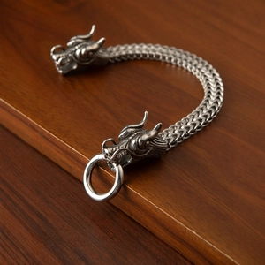 Detalle del brazalete vikingo cabeza de lobo en acero con textura de escamas trenzadas