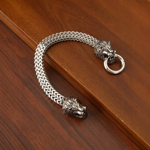 Detalle de pulsera vintage de acero inoxidable con cabezas de león y eslabones trenzados