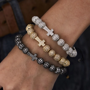 Close-up of three hip hop beaded bracelets with iced-out cross charms in gold, silver, and black
