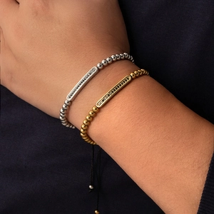 Detail von verstellbaren Perlenarmbändern in Gold und Silber mit schwarzem Zirkonia-Stab