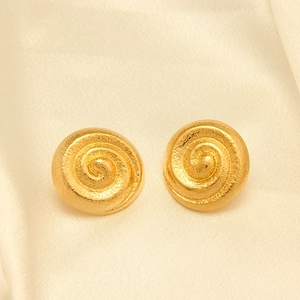 Details von goldenen Spiralschnecken-Ohrringen mit Hammerschlag-Textur auf Seide