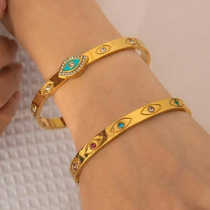 Detail shot of stacked gold evil eye bracelets featuring colorful cubic zirconia and enamel